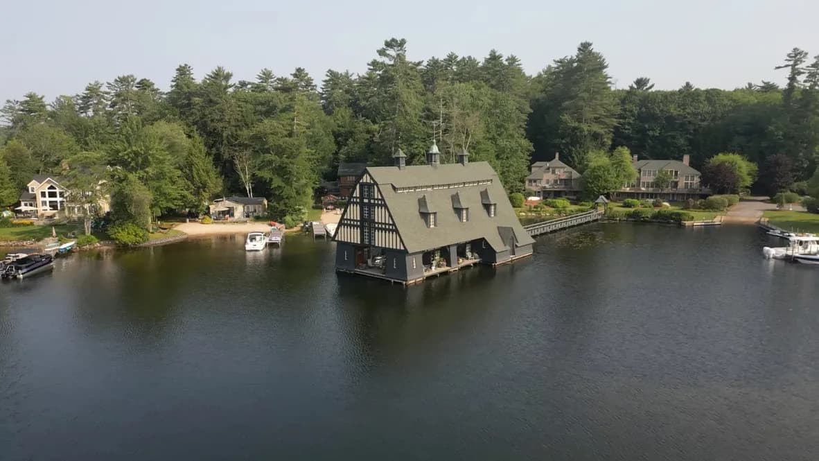 Aerial drone view of a waterfront property with dock and boathouse