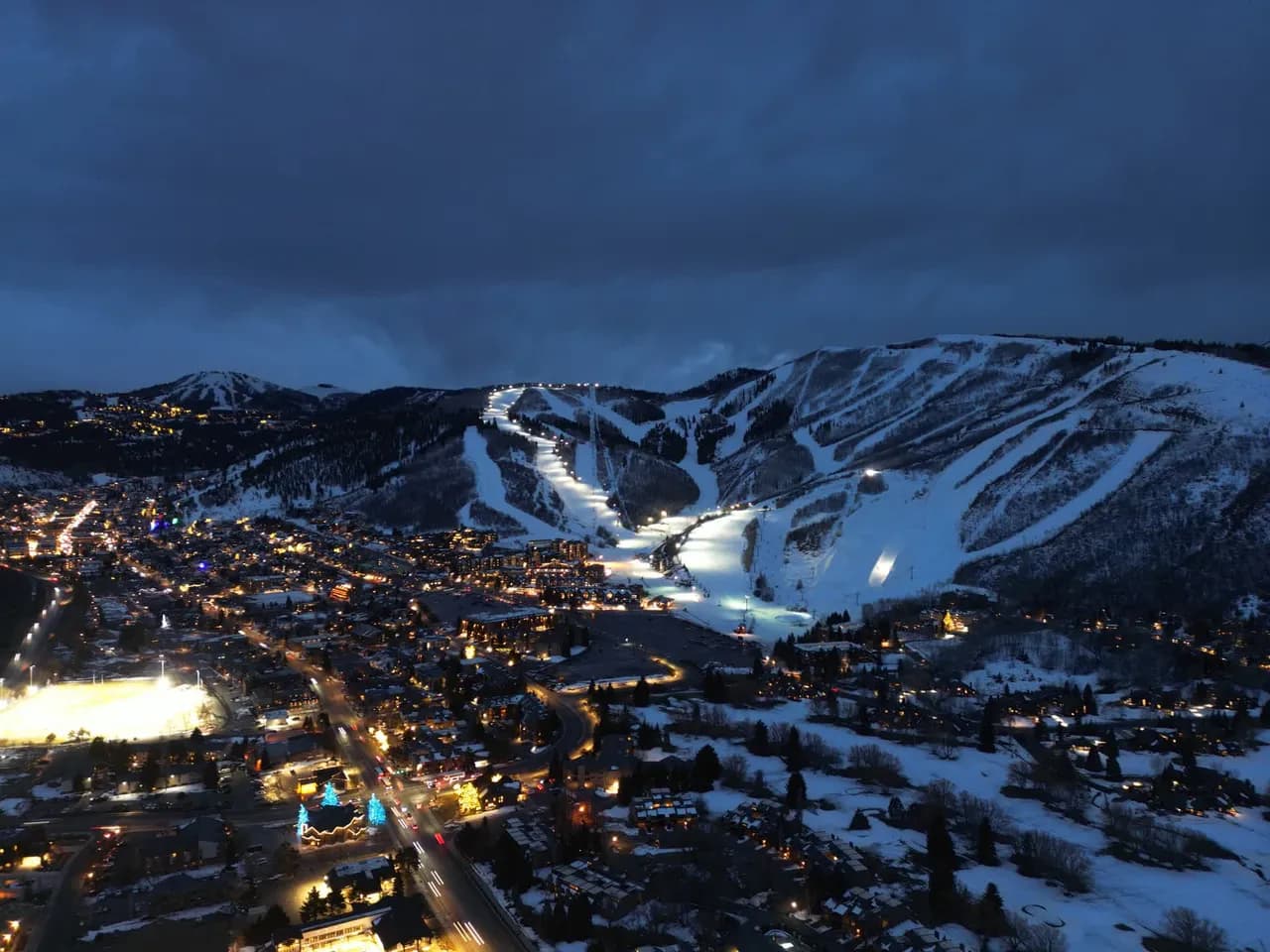 Aerial drone view of a ski resort at night with lit runs