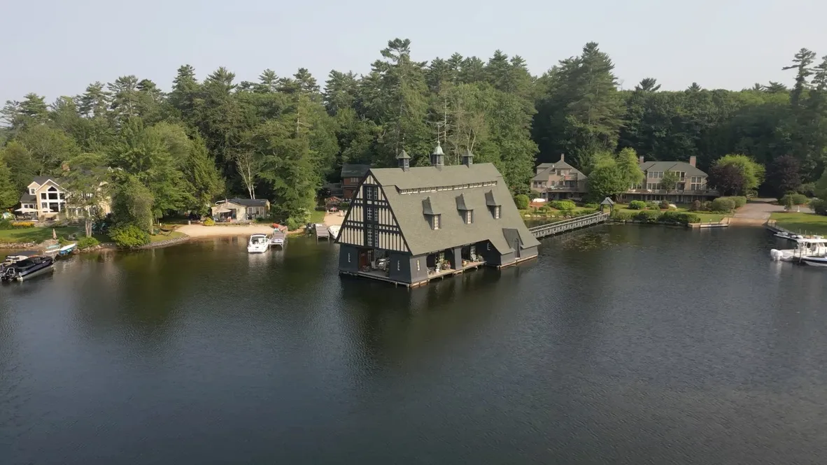Aerial drone view of a waterfront property with dock and boathouse