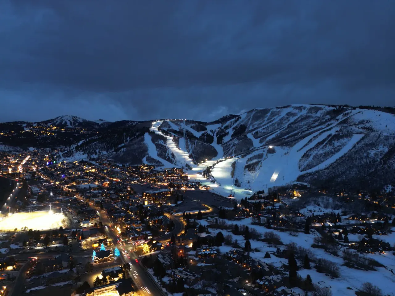 Aerial drone view of a ski resort at night with lit runs